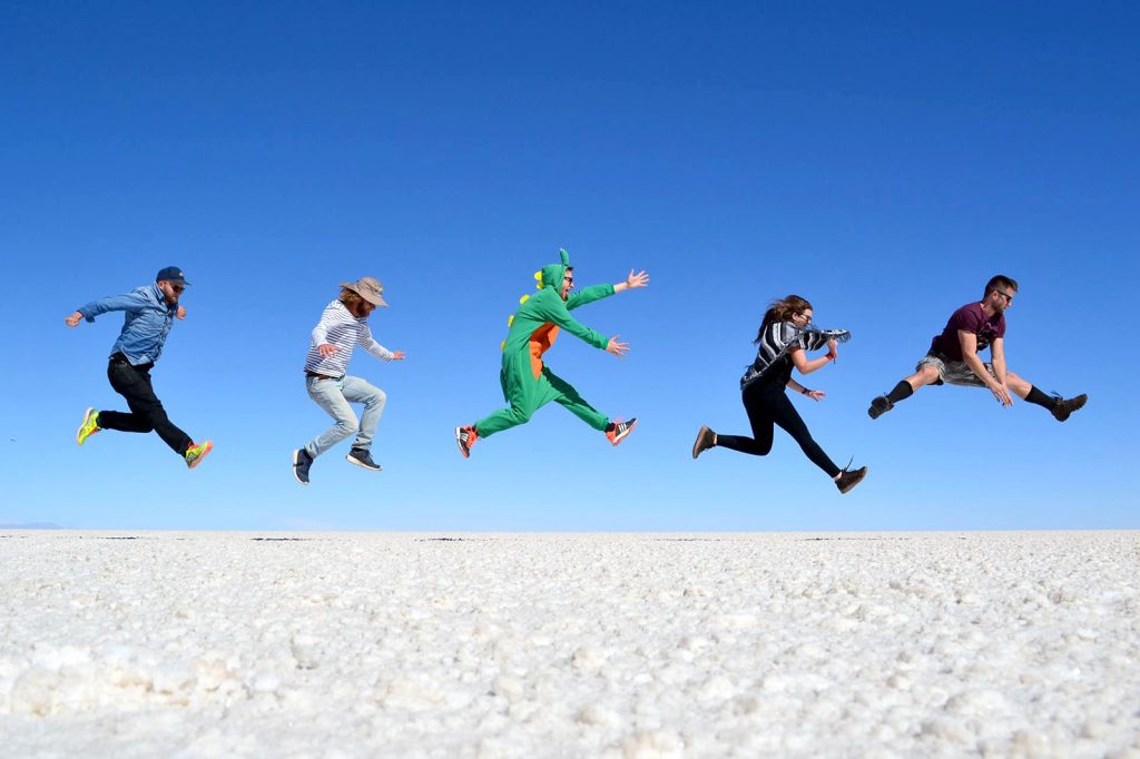 5 viajantes amigos saltando ao mesmo temo no deserto